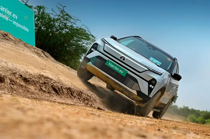 Tata Harrier EV AWD navigating a rocky off-road trail with a scenic mountainous backdrop.