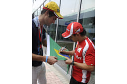 Massa signs a Brazilian flag for a fan.